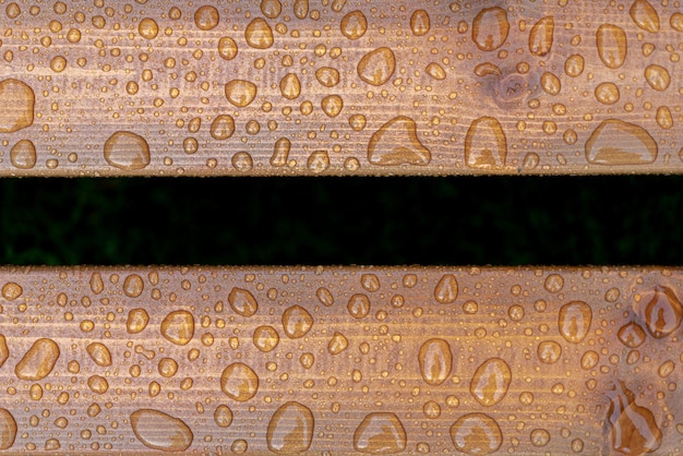 Zdjęcie poziome tło lakierowanej spalonej tekstury drewna z błyszczącą wodą spada z deszczu mokrych drewnianych desek