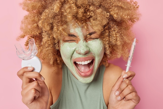 Poziome Ujęcie Emocjonalnej Kobiety Krzyczy Emocjonalnie Nakłada Odżywczą Glinianą Maskę Na Twarz Trzyma Plastikowy Ekspander Do Ust I Strzykawkę Z Płynem Poddaje Się Codziennym Zabiegom Kosmetycznym Stoi W Pomieszczeniu