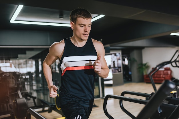 Poziome ujęcie kaukaski mężczyzna lekkoatletycznego bieganie w nowoczesnej siłowni na bieżni robi ćwiczenia cardio Sport fitness zdrowe życie i koncepcja ludzi