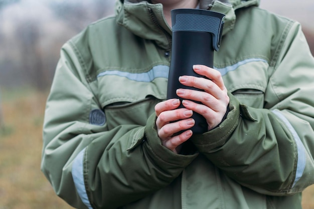 Późną Jesienią Kobiece Dłonie Grzeją Się Na Czarnym Przełączniku Z Gorącym Napojem. Ekologiczne Użycie Okularów Wielokrotnego Użytku.