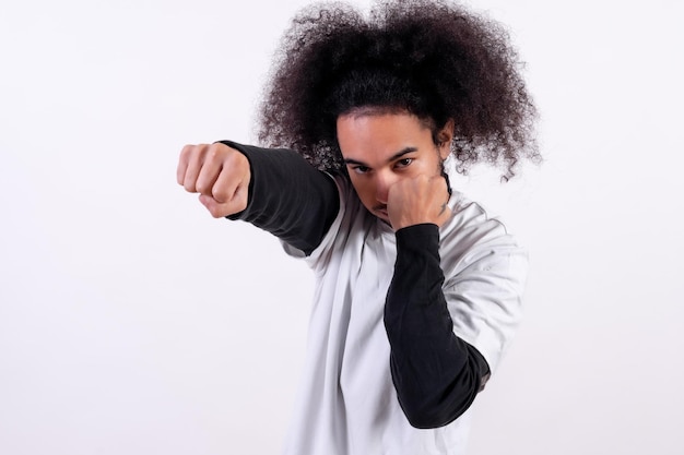Pozycja ataku bokserskiego Młody człowiek z włosami afro na białym tle