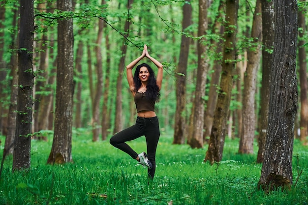 Pozytywna brunetka robi fitness na świeżym powietrzu w lesie w ciągu dnia