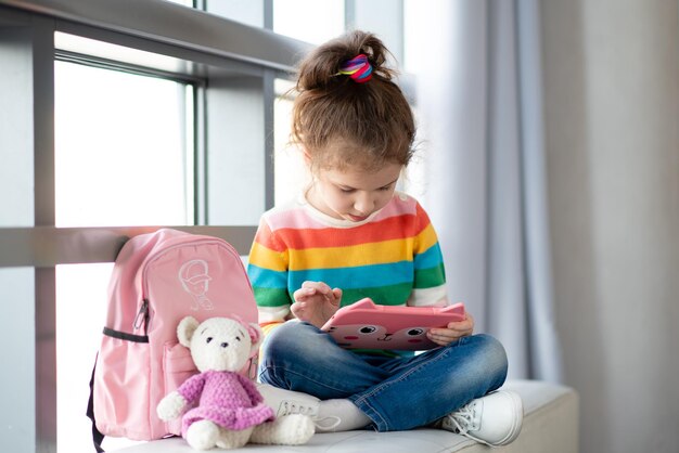 Pozytywna dziewczynka trzymająca komputer w dłoniach Gry Dzieci korzystają z technologii