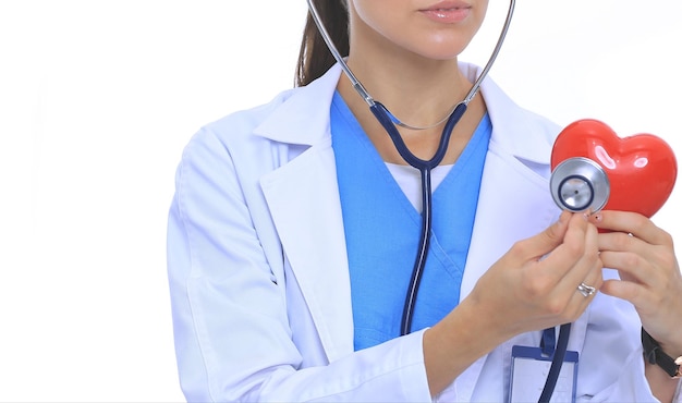 Pozytywna lekarka stojąca ze stetoskopem i symbolem czerwonego serca na białym tle Kobieta lekarz