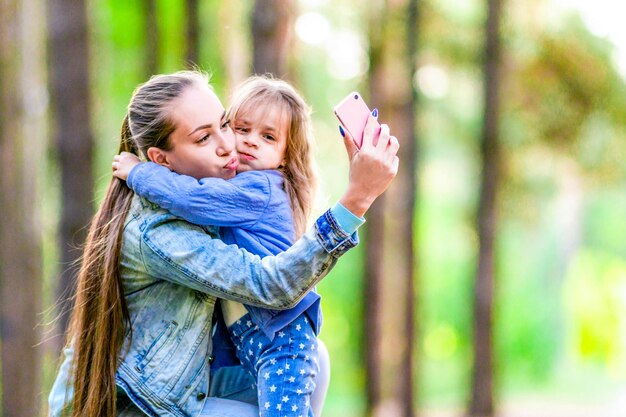 Pozytywna mama i córka robią sobie selfie na spacer po lesie Zabawny nastrój Letni słoneczny dzień