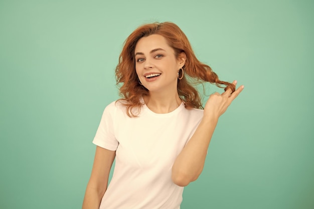 Pozytywna ruda dziewczyna z kręconymi włosami na niebieskim tle