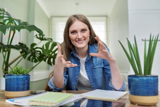 Pozytywna uśmiechnięta studentka uniwersytetu rozmawiająca patrząc na kamerę internetową w domu