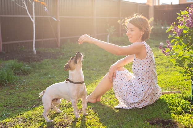 Pozytywna, wesoła kobieta bawiąca się z ukochanym psem Jack Russell Terrierem na podwórku swojego kraju