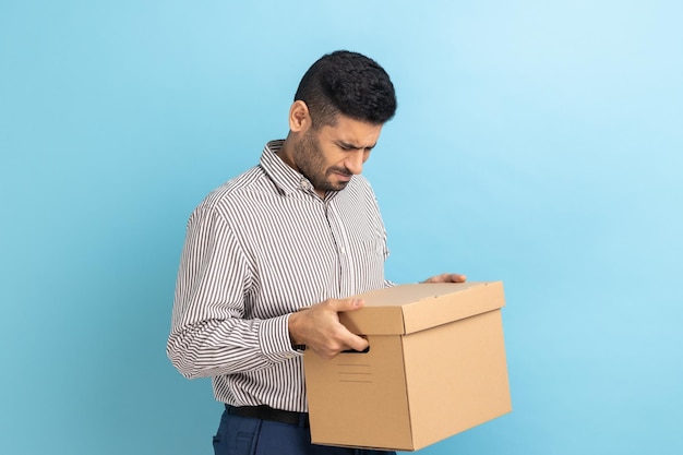 Zdjęcie pozytywny biznesmen trzyma kartonową paczkę dostarczającą zamówienia na adres patrząc na opakowanie kartonowe