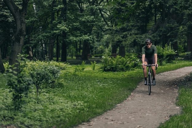 Pozytywny człowiek w sportowej jeździe na rowerze w parku miejskim