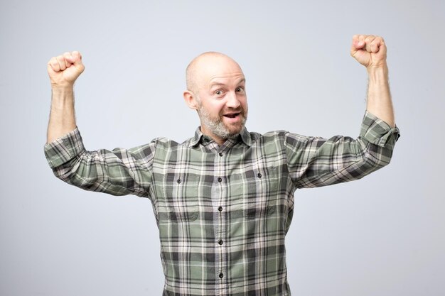 Zdjęcie pozytywny emocjonalny mężczyzna uśmiecha się, pokazując mięśnie ramion, które są dumne z bycia silnym