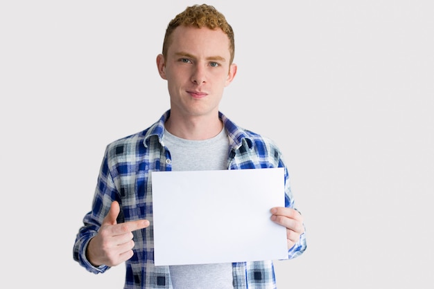 Zdjęcie pozytywny młody człowiek pokazuje pustego papier przy kamerą
