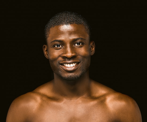 Pozytywny nagi amerykanina afrykańskiego pochodzenia mężczyzna toothy uśmiechy patrzeje kamerę.