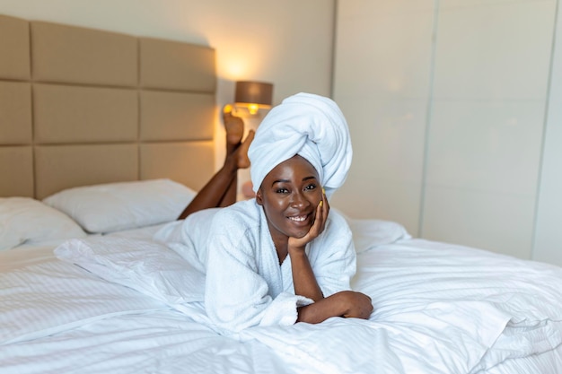 Pozytywny Początek Dnia Uśmiechnięta Afrykańska Młoda Kobieta Leżąca Na łóżku W Szlafroku Afroamerykanka Relaksuje Się Na łóżku Po Kąpieli I Patrzy W Kamerę