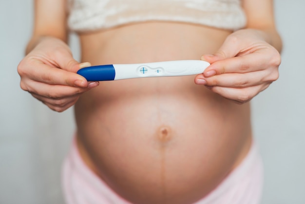 Pozytywny test ciążowy w rękach kobiety w ciąży