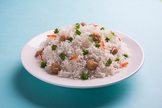 Pożywny sojowy pulao lub pilaf lub smażony w kawałkach sojowy ryż z zielonym groszkiem i fasolą. Podawane w misce na kolorowym lub drewnianym tle. Selektywne skupienie