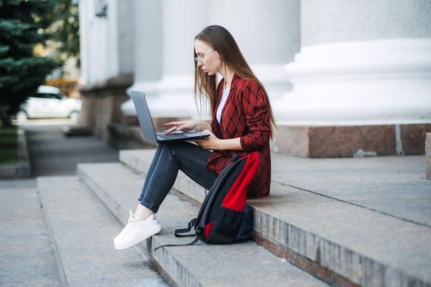 Praca online dla studentów uczelni młoda kobieta studentka dziewczyna szukająca pracy z laptopem na zewnątrz