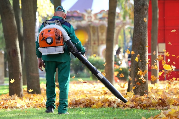 Praca w Parku usuwa jesienne liście za pomocą dmuchawy