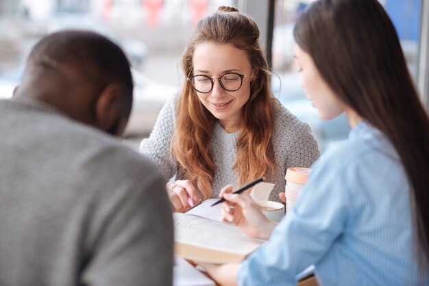 Praca Zespołowa. Trzej Studenci Z Zagranicy Uczą Się Razem, Siedząc W Lekkiej Kawiarni Podczas Przerwy Obiadowej.