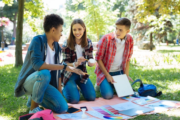 Pracować Na Zewnątrz. Trzech Promieniejących Obiecujących Studentów Sztuki, Cieszących Się Z Pracy Nad Projektem Na Zewnątrz