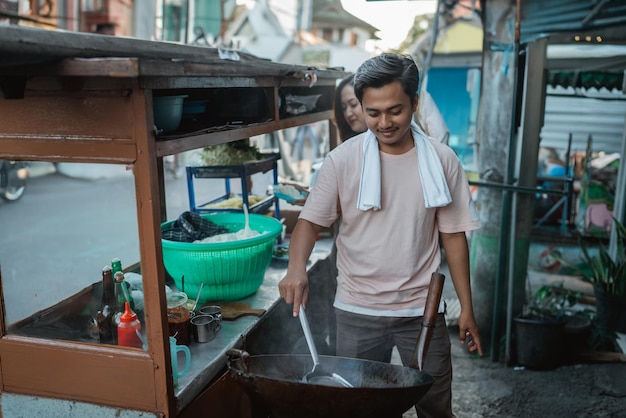 Zdjęcie pracowity mężczyzna mieszając gorący wok, gotując smażony ryż orientalne potrawy