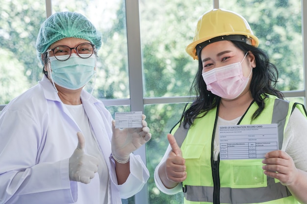 Pracownica i pielęgniarka pokazujące kartę szczepień przeciwko Covid 19 po wstrzyknięciu szczepionki