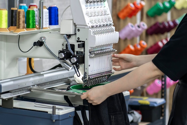 pracownica używająca i przygotowująca automatyczną maszynę do szycia do pracy w fabryce odzieży