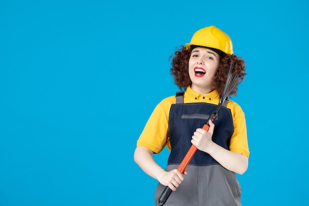 Pracownica w żółtym mundurze z narzędziem ogrodowym na niebiesko