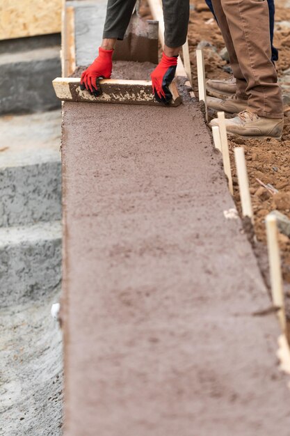 Pracownicy Budowlani Wylewają I Wyrównują Mokry Cement Do Konstrukcji Drewnianych