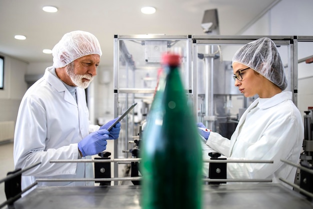 Pracownicy linii produkcyjnej lub technolodzy kontrolujący produkcję wody butelkowanej w opakowania PET