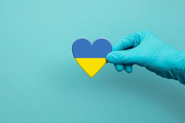 Pracownicy medyczni ręka nosząca rękawicę chirurgiczną trzymającą flagę ukrainy w sercu