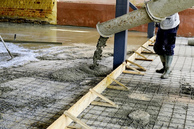 Zdjęcie pracownicy wyrównujący beton nowego budynku