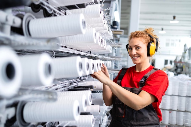 Zdjęcie pracowniczka pracująca w fabryce włókienniczej sprawdzająca przemysłową maszynę do szycia