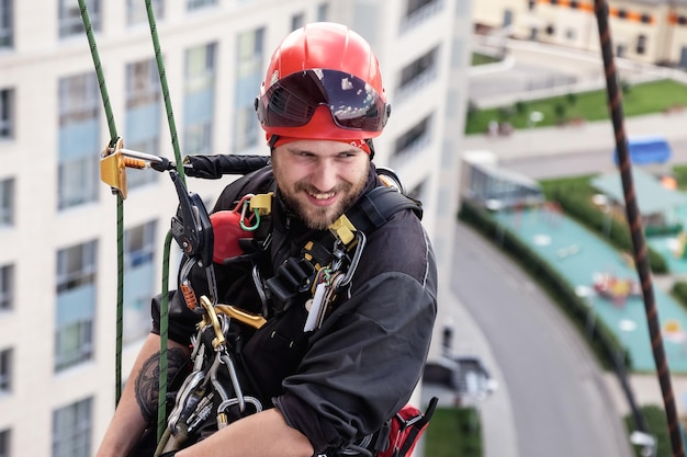 Pracownik alpinizmu przemysłowego wisi nad fasadą budynku mieszkalnego