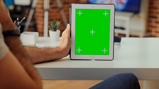 Pracownik biurowy posiadający cyfrowy gadżet pokazujący szablon greenscreen, analizujący na białym tle wyświetlacz makiety z kluczem chroma. Praca z bezprzewodowym tabletem i pustą przestrzenią. Ścieśniać.