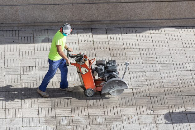 Pracownik budowlany cięcia kostki brukowej z diamentowej piły tarczowej na chodniku