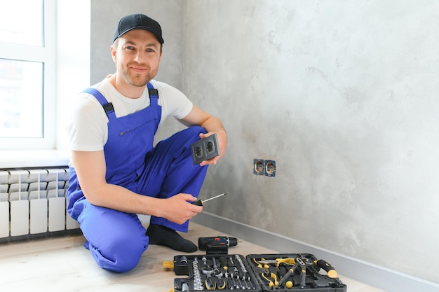 Pracownik budowlany elektryk montuje gniazdko elektryczne w mieszkaniu