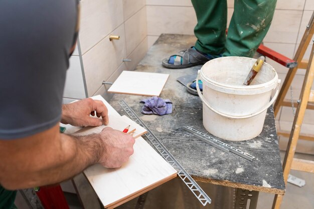 Zdjęcie pracownik budowlany mierzy i przygotowuje się do cięcia płytek ceramicznych