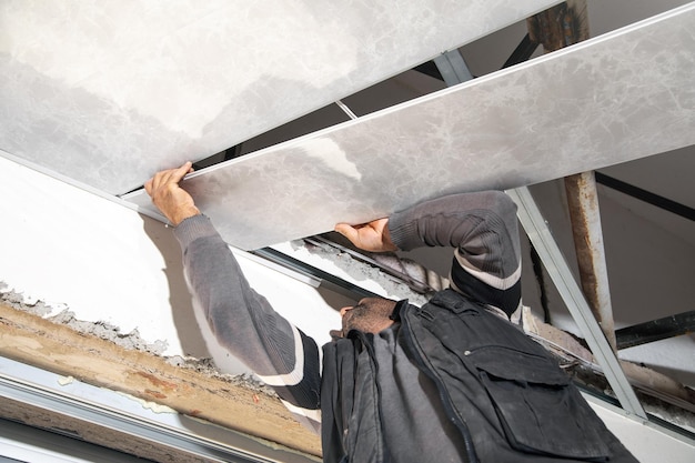 Pracownik budowlany montuje sufit podwieszany