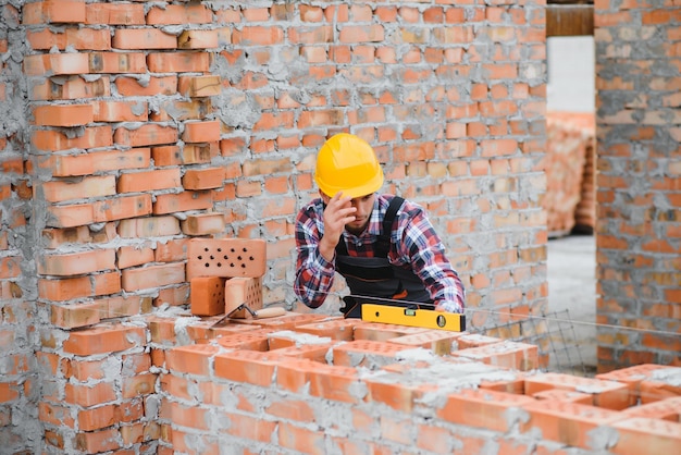Zdjęcie pracownik budowlany w mundurze i sprzęcie ochronnym ma pracę przy budowie tematu przemysłowego