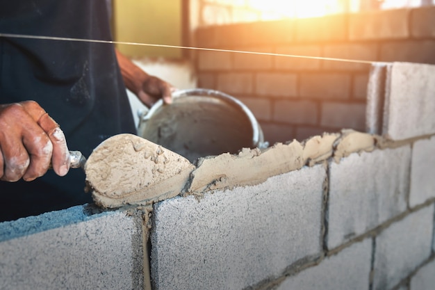 Zdjęcie pracownik buduje ścienne cegły z cementem