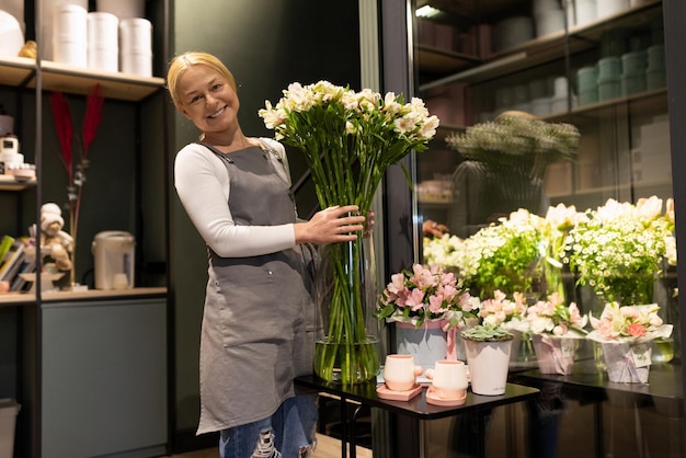 Pracownik butiku florystycznego trzymający w rękach świeże kwiaty