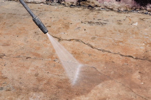 Pracownik czyszczący brudną podłogę myjką wysokociśnieniowąxA