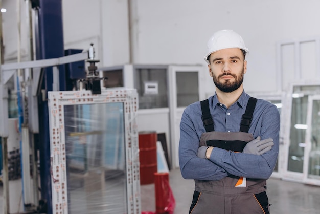 Pracownik fabryczny pozujący z skrzyżowanymi ramionami w fabryce okien i drzwi z aluminium i PVC