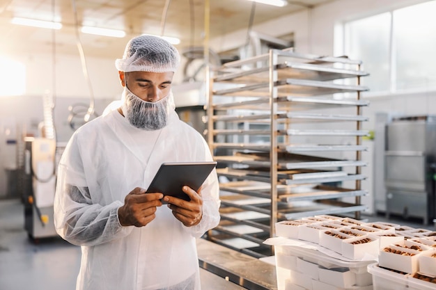 Pracownik fabryki żywności używający tabletu i sprawdzający pliki cookie