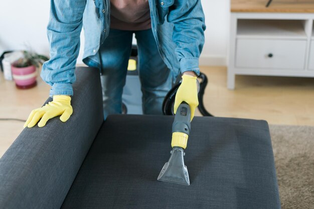 Pracownik firmy sprzątającej usuwający brud z mebli w mieszkaniu za pomocą profesjonalnego sprzętu m.in