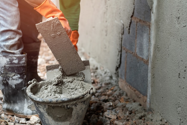 Pracownik gipsuje cement na ścianie dla budować dom