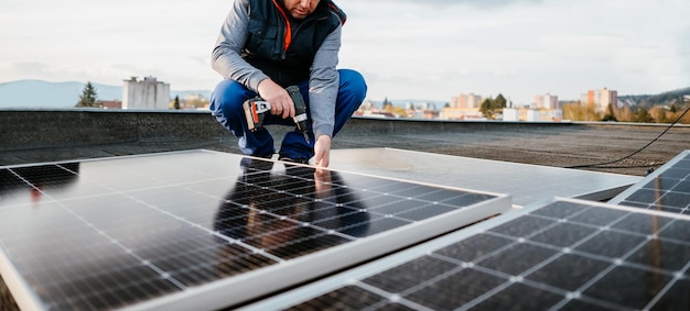 Pracownik instalujący nowe panele słoneczne na dachu domu jednorodzinnego Energia alternatywna Zdjęcie na okładce