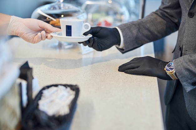 Zdjęcie pracownik kafeterii podający kupującemu filiżankę kawy