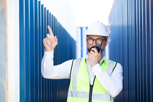 Zdjęcie pracownik kontenera używający talky talky do komunikacji w logistyce przemysłu towarowego. zarządzanie biznesowe przygotowuje się do wysyłki produktu do klienta.